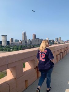 a person in a Cleveland Indians jersey crosses a bridge in front of the city skyline